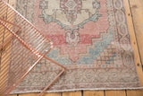Distressed vintage Oushak runner's soft texture in faded pink, blue, and beige.