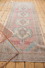 Distressed Oushak runner with central medallions, softened pink, powder blue, and beige abrashes.