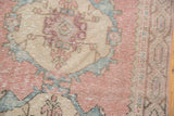 Textured blush pink, beige, and powder blue Oushak rug fragment with stepped spandrel and even wear.