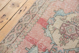 Distressed texture and geometric border of a vintage Oushak rug in blush pink, beige, and blue.