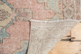 Distressed vintage Oushak rug pile with even wear, pastel pinks, blues, and woven foundation.