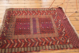 Corner view of a vintage Turkmen rug with red and ivory geometric borders, rams horn motifs, and fringe.