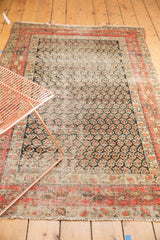 Antique Hamadan rug corner, showing fringed edge, brick red borders, and navy boteh field.