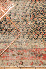 Antique Persian Hamadan rug detail: staggered boteh pattern, border, deep navy, brick red, and sand tones.