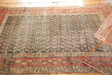 Detail of antique Hamadan rug showing dark navy boteh field and brick red paisley border.