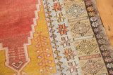 Geometric borders of a vintage Melas rug in softened terracotta, saffron, with a finished edge.
