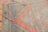 Distressed Oushak rug corner with intricate lattice spandrel, short pile, dusty rose, beige.