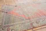 Distressed Oushak rug corner, showing intricate lattice spandrel and dusty rose field.