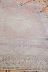 Distressed Oushak rug showing worn texture, time-softened hues, and faded geometric details.