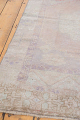 Decorative distressed texture and secured edge of vintage Oushak rug, revealing muted tones.