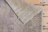 Vintage distressed Oushak rug corner, revealing worn pile, muted colors, and hand-knotted backing.