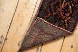 Antique Kurdish fragment rug, showing hand-knotted reverse, red, teal, navy tones, and fringe.