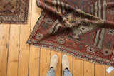 Intricate geometric Qashqai patterns in chestnut, navy, ivory, featuring the rug's tattered fringe.