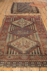 Antique Qashqai rug's lower border with geometric patterns, rich reds, and tattered fringe.