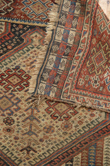 Intricate tribal patterns of an antique Qashqai rug, showcasing worn fringe and exposed foundation.