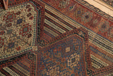 Intricate geometric tribal motifs and aged color variations on the antique Qashqai rug detail.