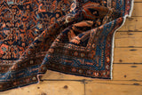 Fringe and geometric navy blue border on a vintage Hamadan rug with floral vinery.