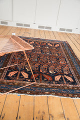 Vintage Hamadan rug corner with large blush and rust serrated leaf on navy, detailed traditional border, and fringe.
