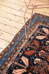 Vintage Hamadan rug corner, navy field with blush serrated leaves, intricate blue border, and fringe.