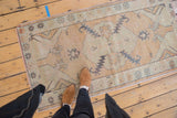 Distressed Oushak runner showing even wear on its beige field and seafoam green motifs.