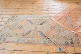 Distressed vintage Oushak runner's corner showing geometric motifs in beige, seafoam, charcoal.