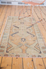Softened beige and seafoam green distressed rug corner with secured fringe.
