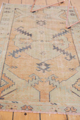 Distressed Oushak rug runner's worn pile, geometric border, and light fringe.