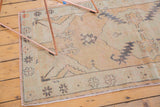 Worn beige pile of vintage Oushak rug with seafoam green and charcoal tribal design.