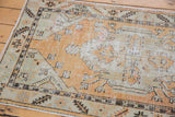Textured wear across a distressed vintage Oushak rug in faded tangerine and seafoam green.