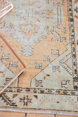 Faded tangerine, pale seafoam green distressed Oushak rug border detail, serrated leaf motif, and fringe.
