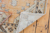 Faded tangerine orange and seafoam geometric vintage Oushak rug corner revealing hand-knotted foundation and wear.