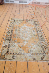 Distressed Oushak rug corner with light fringe, faded tangerine, and green border design.