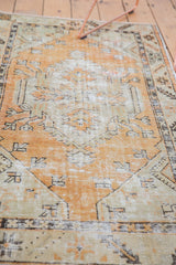 Distressed hand-knotted Oushak rug showing faded tangerine orange, seafoam, ivory pile wear.