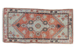 Distressed Oushak runner with a pale cherry red field and seafoam floral medallion.
