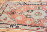 Distressed pile detail of a vintage Oushak runner with cherry red and seafoam green motifs.
