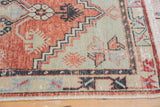 Distressed Oushak rug corner with faded cherry red, seafoam green patterns and light wear.