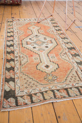 Distressed Oushak rug corner with worn black, ivory geometric border and soft fringe.
