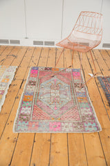 Vibrant pink, blue, and mint shades on a distressed Oushak rug's geometric corner.