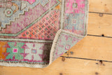 Distressed Oushak rug corner revealing original side cord selvage and worn knot heads.