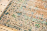 Distressed Oushak rug corner, showcasing heavy wear, visible foundation, faded vintage colors.