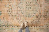Distressed Oushak rug showing pale apricot field, mint green, charcoal vinery, and foundation.