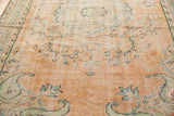 Distressed apricot Oushak rug field with mint green vinery and elongated paisley.