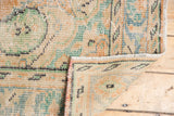 Distressed Oushak carpet with low pile, exposed foundation, and secured side in apricot and mint.