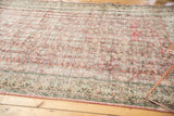 Muted dusty rose distressed Oushak rug with low pile floral field and patterned border.