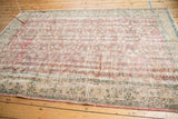 Oushak carpet close-up: distressed dusty rose floral field, antique ivory border detail.