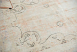 Distressed Oushak carpet with worn texture, charcoal brown pattern, and dusty rose tones.