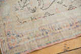 Faded pale blush and blue patterns on a distressed Oushak carpet with low pile.