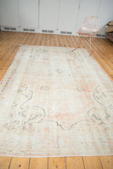 Fringe and worn pile of the distressed Oushak carpet, with dusty rose hues.