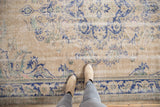 Distressed Vintage Oushak carpet with mostly even wear, featuring faded royal blue and ivory floral patterns.