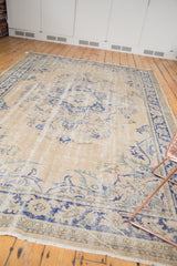 Distressed vintage Oushak carpet end, showing blue floral border and secured fringe.